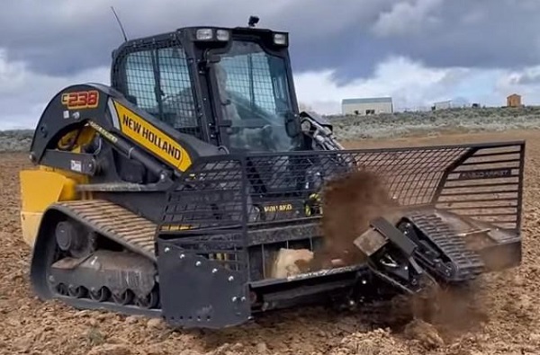 Rock picker attached the front of a small bulldozer