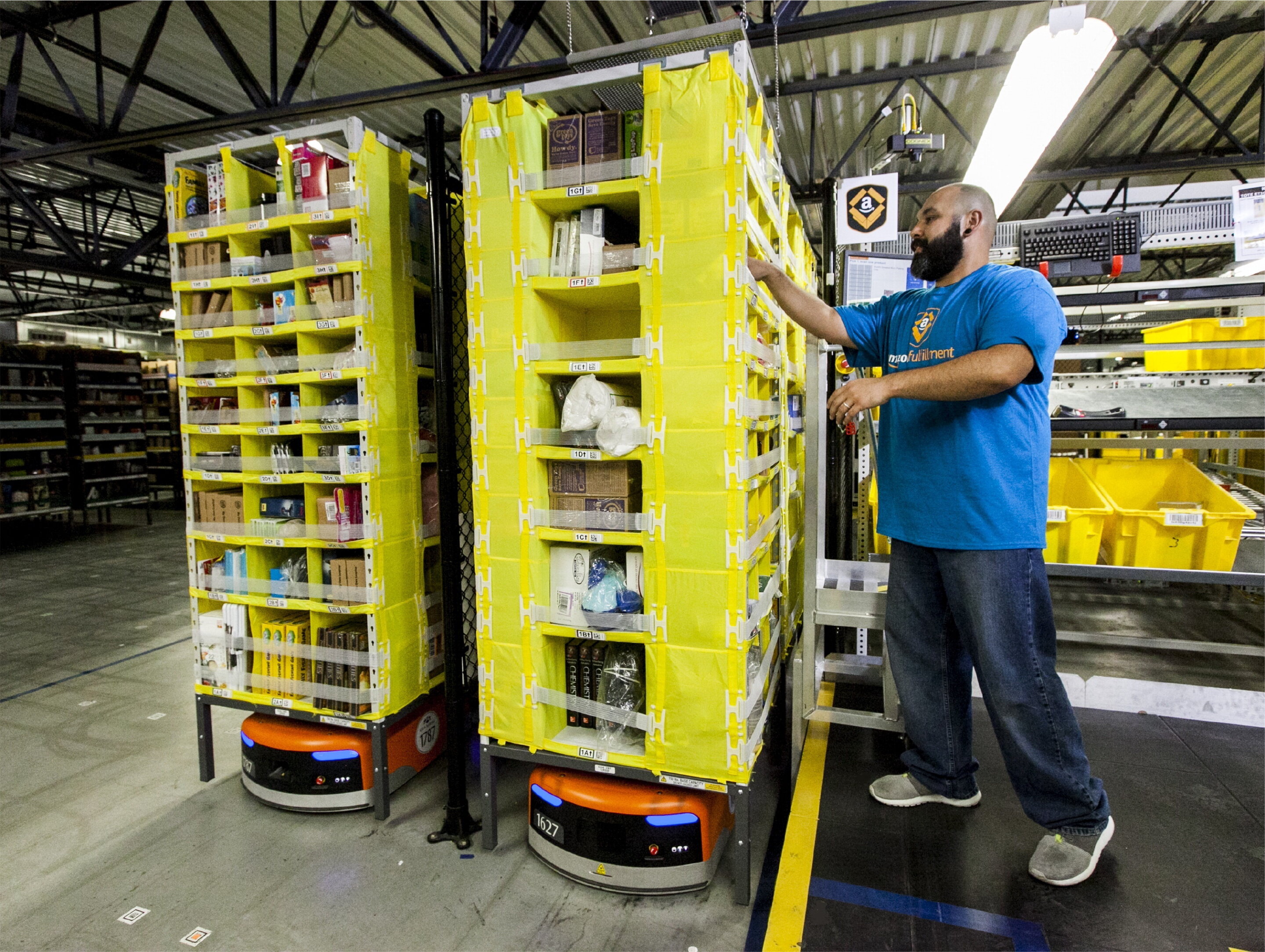 worker in amazon robotic fulfillment center has goods delivered to him