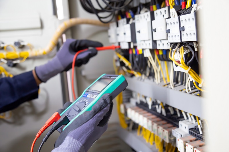 Electrician measuring voltage in a cabinet