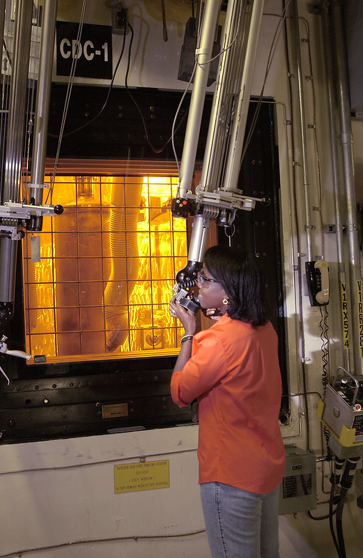 worker manipulations a robotic arm during nuclear waste processing
