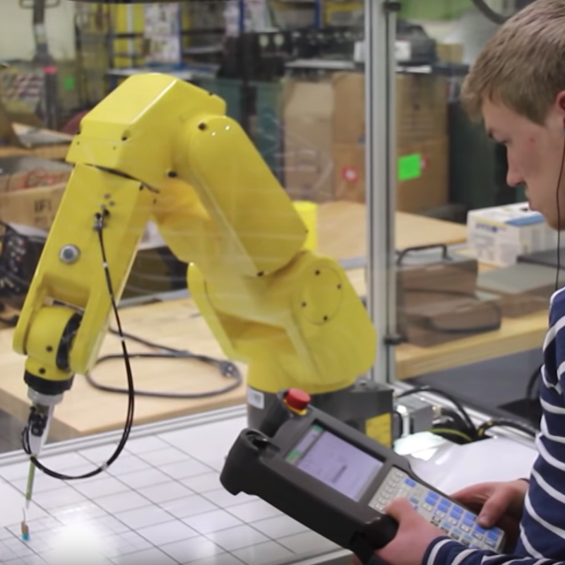 A student at Hennepin Technical College working with control systems and robots